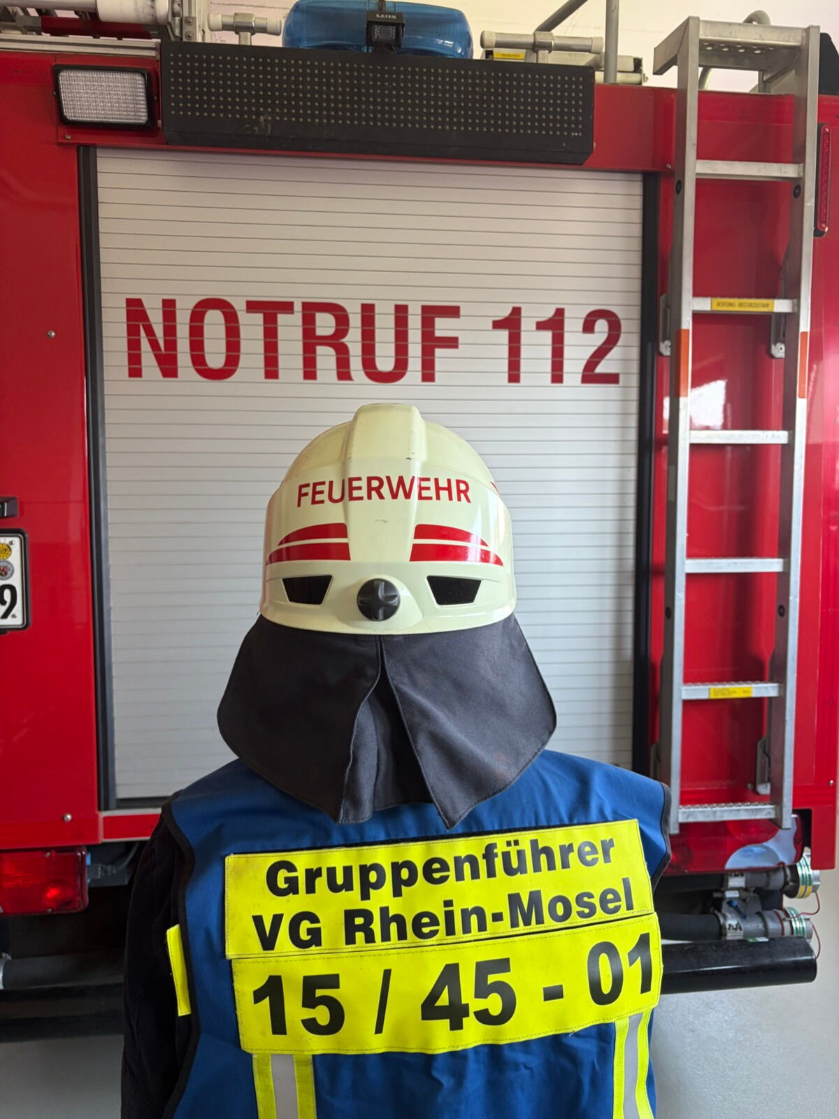 Gruppenführer mit Weste und Helm von Hinten